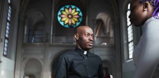 Priest speaking with a visitor inside a church