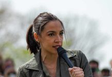 AOC speaking into a handheld microphone outdoors