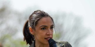 AOC speaking into a handheld microphone outdoors