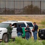Trumps TOP Man Immediately QUITS – No Explanation! law enforcement officers confer beside patrol vehicles near a border fence