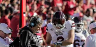 Mississippi State football coach and quarterback review play card on sideline