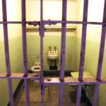 DSA Leader VOWS To SHUTDOWN Federal Prisons Interior of a prison cell with a toilet, sink, and metal bars