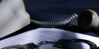 Handcuffs on a document beside a coiled telephone handset