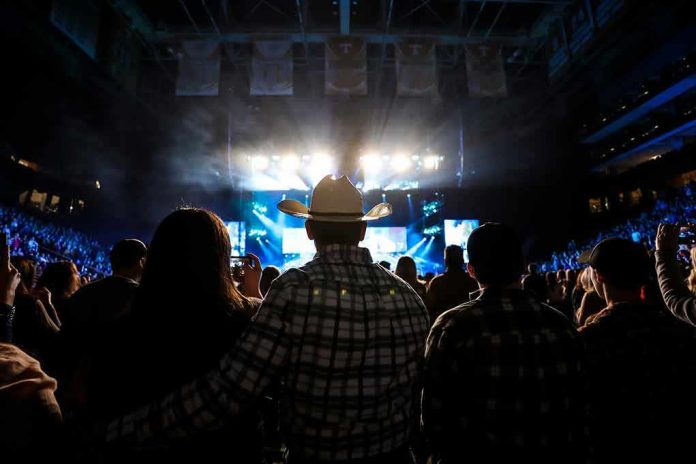 Cowboy-hatted man watches a concert in a packed arena