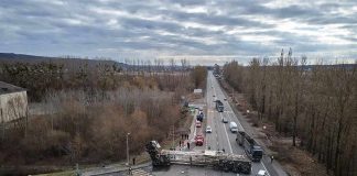 Overturned semi-trailer blocks highway at rural intersection