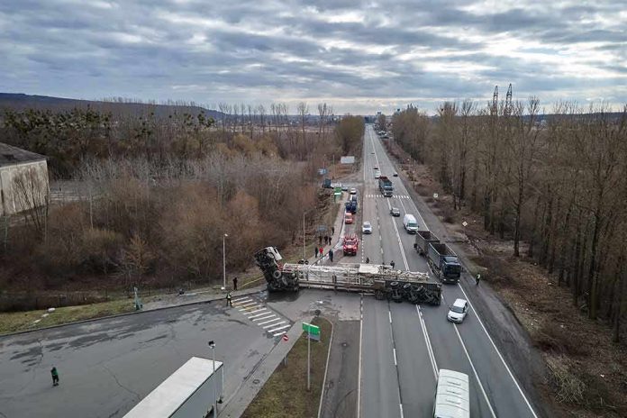 Overturned semi-trailer blocks highway at rural intersection