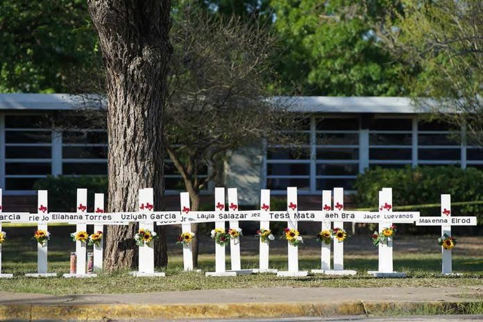 Row of white memorial crosses with flowers outside a building