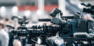Broadcast cameras on tripods at a press event