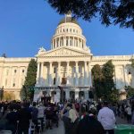 Crowd gathers before a neoclassical capitol building with dome