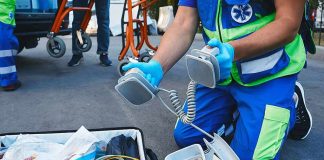 Paramedic kneeling with defibrillator paddles