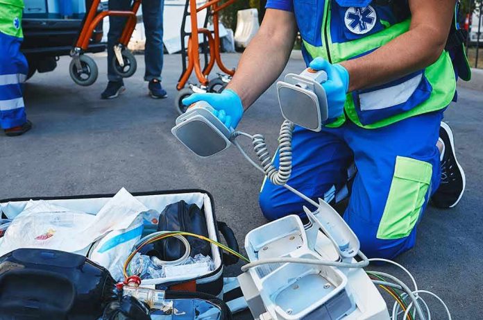 Paramedic kneeling with defibrillator paddles
