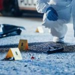 Gruesome Discovery Outside Iran’s World Cup Training Camp Stuns! Forensic investigator examines a crime scene with evidence markers and a handgun