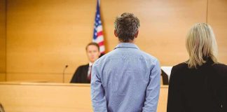 Defendant in handcuffs standing before a judge in a courtroom
