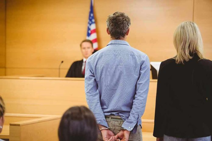Defendant in handcuffs standing before a judge in a courtroom