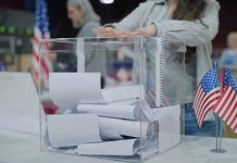 Person casting a ballot into a clear box at a polling station