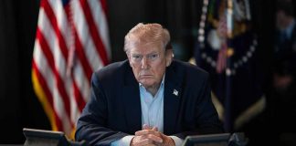 Trump Tells Americans to Pay Their Fair Share Person in suit seated at table with telephones