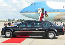 Presidential limousine beside a large blue-and-white jet on a runway