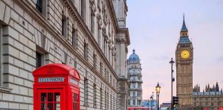 Red telephone box on a London street with clock tower in background