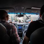 Dashboard Surveillance Mandated — U.S. Next driver and passenger inside a car in city traffic
