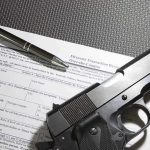 Handgun on firearm transaction form with pen