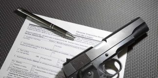Handgun on firearm transaction form with pen