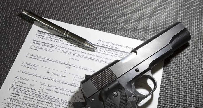 Handgun on firearm transaction form with pen