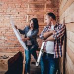 Workers FIND $10 Million During Construction Dig Two people reviewing blueprints in a rustic room under renovation