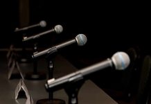 Row of microphones on stands at a panel table