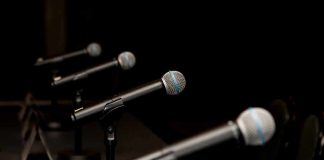 Row of microphones on stands at a panel table