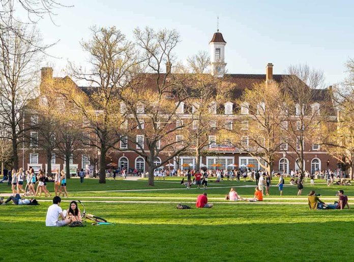 shutterstock_1037739901 Students relaxing on a campus quad in front of a brick academic building