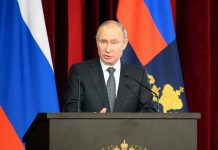 Vladimir Putin speaking at a podium with microphones