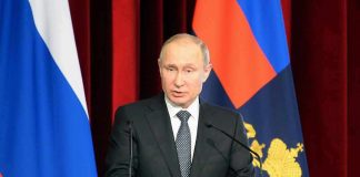 Vladimir Putin speaking at a podium with microphones