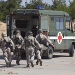 Soldiers running towards a medical vehicle during a military operation