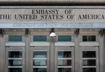 United States embassy entrance with metal doors and security camera