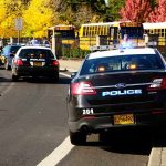 Hero Bystander GUNS DOWN School Shooter Police cars with lights on near school buses on a city street