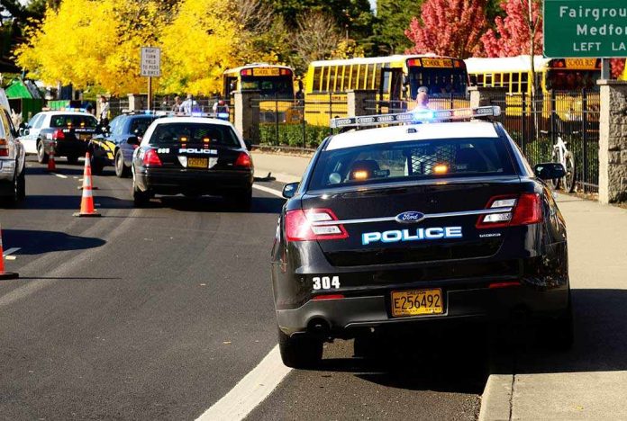 shutterstock_117302929-2- Police cars with lights on near school buses on a city street