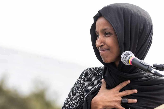 shutterstock_1369296269 Ilhan Omar speaking at a microphone with hand on chest
