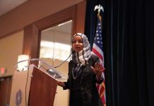 Ilhan Omar speaking at a podium with a microphone