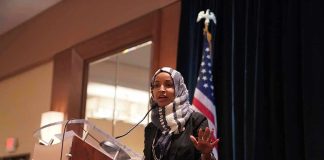 FBI Seize Omars Passport and Phone! Ilhan Omar speaking at a podium with a microphone
