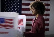 Voter at a polling booth with an American flag backdrop
