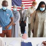 Official Teaches Illegals How to Vote With No ID and Same-Day Registration Voters wearing masks stand in line at a polling station