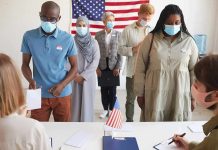 Voters wearing masks stand in line at a polling station