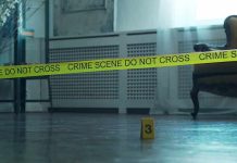 Crime scene tape across a room with evidence marker on floor