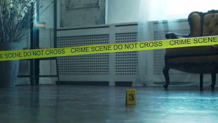 shutterstock_2196208533 Crime scene tape across a room with evidence marker on floor