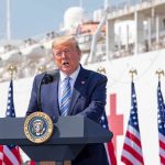 Trump Declares Military Leakers Should Be Shot Donald Trump speaking at a podium with American flags and a ship in the background
