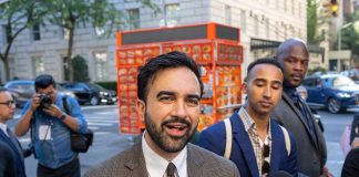 Zohran Mamdani speaking to reporters on a city sidewalk