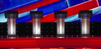 Debate stage with four empty podiums and bright red and blue backdrop