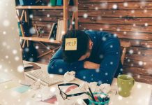 Person with head down at messy desk in home office