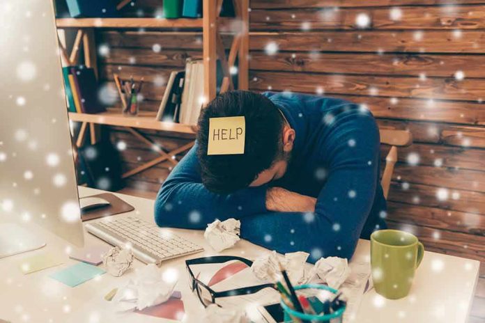 Person with head down at messy desk in home office