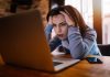 Woman frustrated at laptop, holding her head.